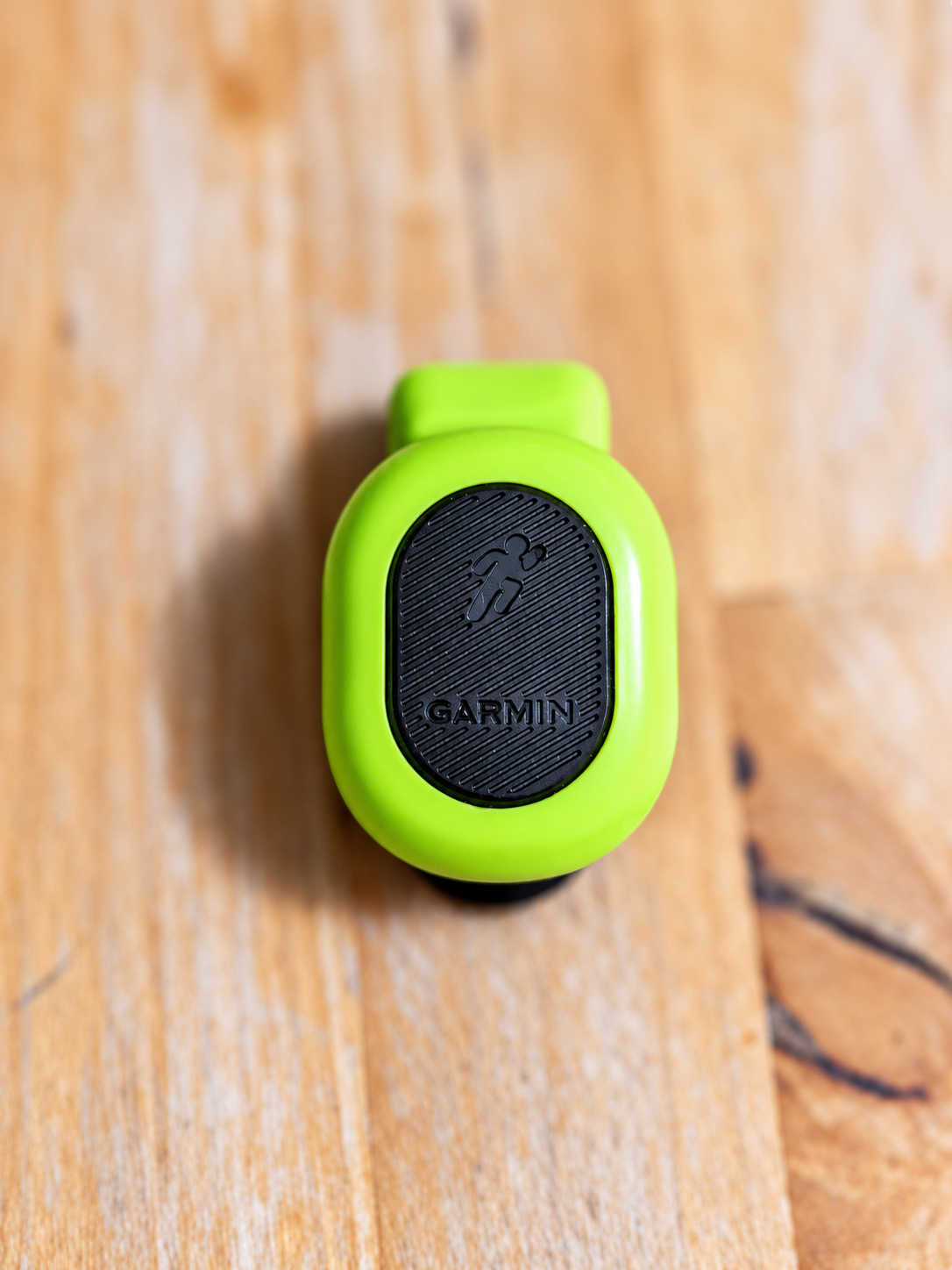 木目の上に置いた緑色のGarmin Running Dynamics Pod本体